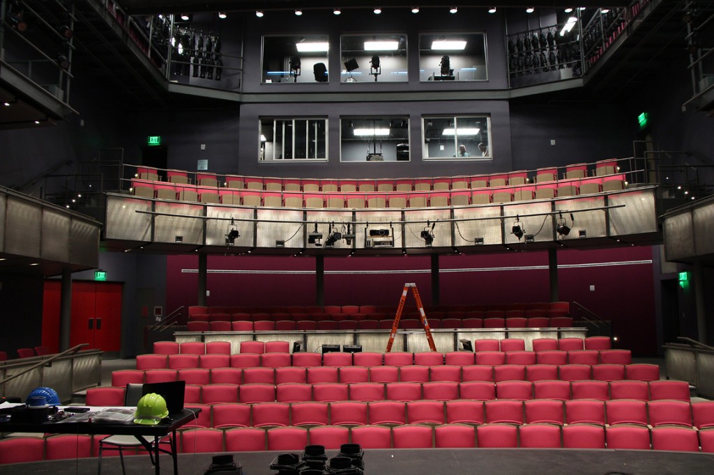 House of the Proscenium Theatre. Several rows of red seats visible, with a balcony level.